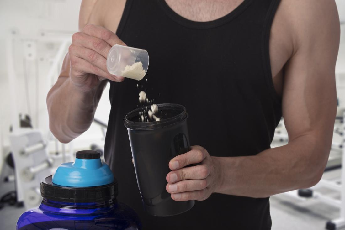 sportsman adding protein powder to drink